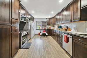 Kitchen with tasteful backsplash, recessed lighting, stainless steel appliances, dark brown cabinets, and light wood-type flooring