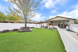 View of yard featuring outdoor lounge area, a deck, a fenced backyard, and a jacuzzi