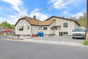 View of front of house with roof with shingles, a chimney, and uncovered parking