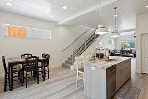Kitchen featuring recessed lighting, a sink, light wood-type flooring, stainless steel dishwasher, and an island with sink