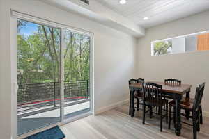 Dining area with recessed lighting, wooden ceiling, light wood-style floors, baseboards, and window with balcony