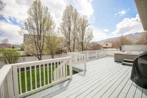 Wooden terrace with a mountain view, a fenced backyard, and a lawn