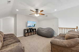 Living area featuring carpet floors, lofted ceiling, and visible vents