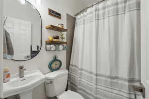 Bathroom with a shower with shower curtain, a sink, and toilet