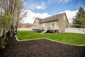 Rear view of property featuring a lawn, a wooden deck, a shingled roof, and a fenced backyard