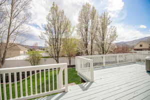 Wooden deck with a lawn, a fenced backyard, and a mountain view