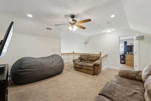 Living area with baseboards, visible vents, lofted ceiling, carpet, and a textured ceiling
