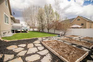 View of yard with a fenced backyard, a wooden deck, and a vegetable garden