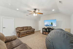 Living room with a ceiling fan, light carpet, vaulted ceiling, and visible vents