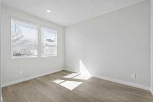 Unfurnished room featuring visible vents, baseboards, and wood finished floors