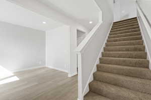 Stairs with recessed lighting, baseboards, and wood finished floors
