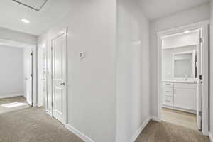 Hallway featuring a sink, baseboards, recessed lighting, and light colored carpet