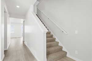 Stairway featuring baseboards, recessed lighting, wood finished floors, and visible vents