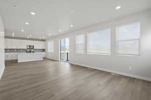Unfurnished living room with visible vents, a sink, baseboards, light wood-style floors, and recessed lighting