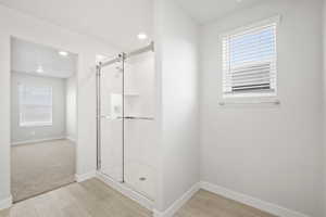 Bathroom with a shower stall, wood finished floors, and plenty of natural light