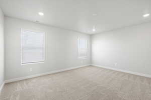 Empty room featuring recessed lighting, light colored carpet, and visible vents