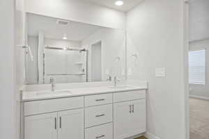 Full bathroom featuring baseboards, visible vents, a shower stall, and a sink