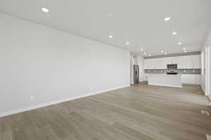 Unfurnished living room featuring recessed lighting, light wood-style floors, baseboards, and visible vents