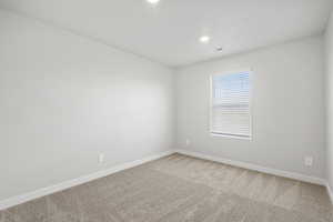 Carpeted empty room featuring baseboards, recessed lighting, and visible vents