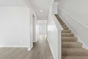 Stairway featuring recessed lighting, baseboards, and wood finished floors