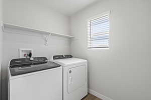 Washroom with baseboards, laundry area, washing machine and dryer, and dark wood-style flooring