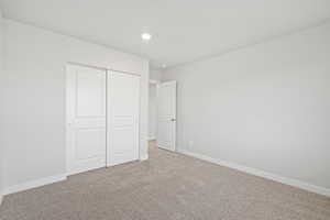 Unfurnished bedroom featuring recessed lighting, baseboards, light carpet, and a closet
