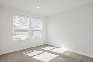 Spare room with visible vents, carpet, and baseboards