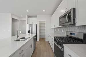 Kitchen featuring a sink, light wood finished floors, light stone countertops, and stainless steel appliances