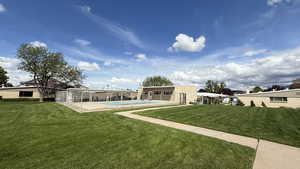 Back of property featuring a patio, a yard, and an outdoor pool