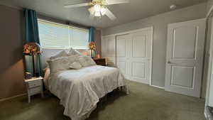 Carpeted bedroom with a closet, ceiling fan, and baseboards