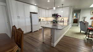 Kitchen featuring stainless steel microwave, white cabinetry, freestanding refrigerator, recessed lighting, and a peninsula