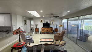 Carpeted living room featuring recessed lighting, a skylight, a ceiling fan, and plenty of natural light