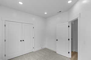 Unfurnished bedroom featuring recessed lighting, light colored carpet, a closet, baseboards, and visible vents