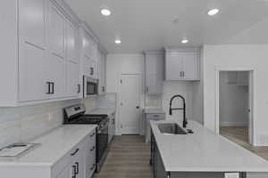 Kitchen with a kitchen island with sink, a sink, wood finished floors, and stainless steel appliances
