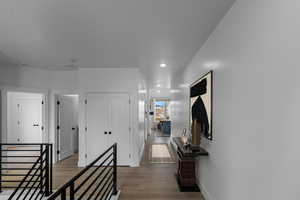 Hallway featuring baseboards, recessed lighting, wood finished floors, and an upstairs landing