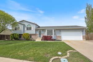Split level home with driveway, a garage, fence, and brick siding
