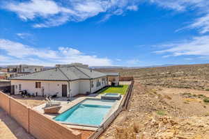 View of swimming pool featuring a fenced backyard, a patio area, a pool with connected hot tub, and a mountain view