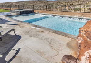 View of swimming pool with a fenced backyard, a mountain view, a pool with connected hot tub, and a patio area