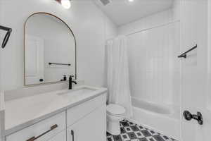 Full bathroom with vanity, shower / bathtub combination with curtain, and toilet