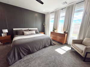 Bedroom featuring multiple windows, light carpet, ceiling fan, and visible vents