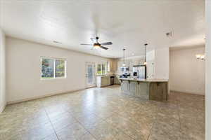 Kitchen featuring visible vents, baseboards, appliances with stainless steel finishes, and ceiling fan with notable chandelier