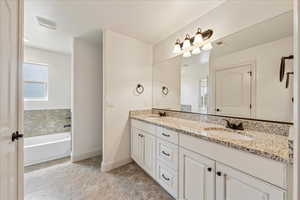 Bathroom with visible vents, a sink, double vanity, and baseboards
