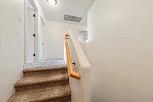 Staircase with visible vents and carpet floors