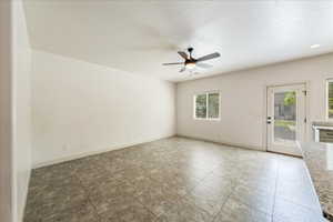 Empty room with ceiling fan, a healthy amount of sunlight, and baseboards