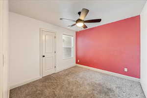 Spare room with baseboards, a ceiling fan, and carpet