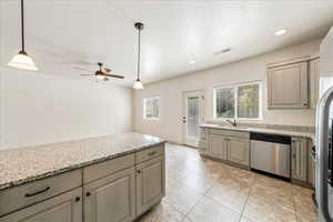 Kitchen with stainless steel dishwasher, light tile patterned floors, ceiling fan, a sink, and visible vents