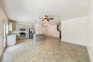 Kitchen with a sink, a breakfast bar, a ceiling fan, baseboards, and appliances with stainless steel finishes