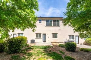 Rear view of house featuring central AC unit, stucco siding, and a patio area