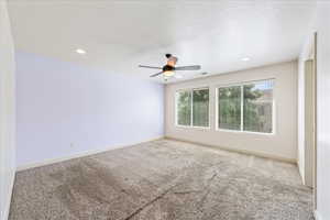 Carpeted spare room featuring ceiling fan, visible vents, and baseboards