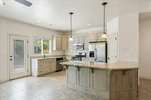 Kitchen with light stone counters, a sink, appliances with stainless steel finishes, a kitchen bar, and recessed lighting